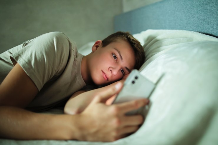 ragazzo a letto con cellulare