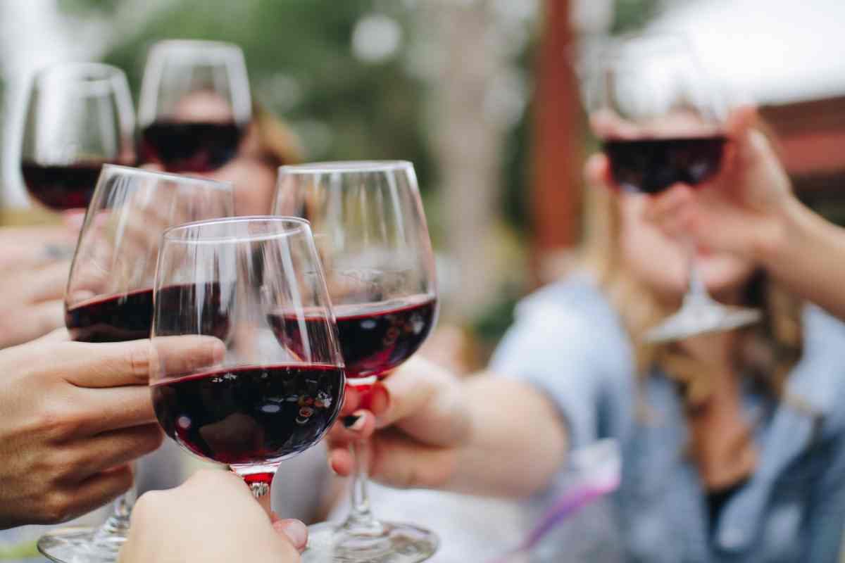 persone che brindano con vino rosso